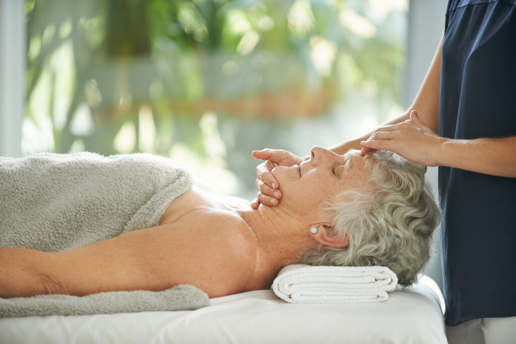 Lissage naturel anti rides réalisé par une praticienne certifiée en massage sur une personne sénior allongée sur le dos, pour un moment de bien-être et de détente, dans un environnement relaxant